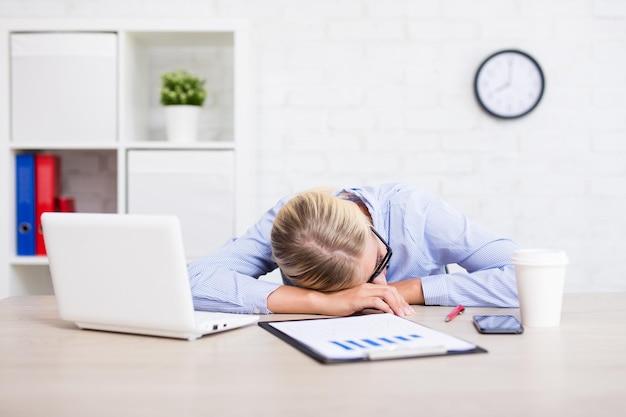 Zmęczona młoda kobieta biznesu śpi w biurze
