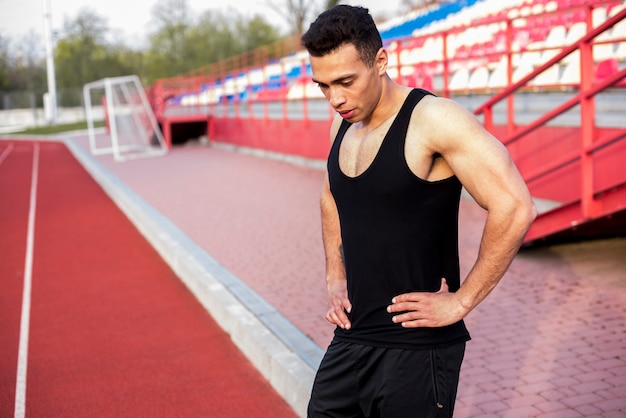 Bezpłatne zdjęcie zmęczona wyczerpana męska atleta stoi na stadium