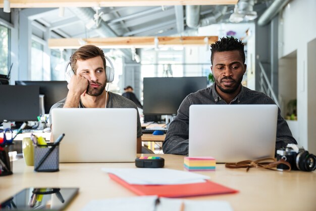 Zmieszani młodzi koledzy siedzi w biurowym coworking