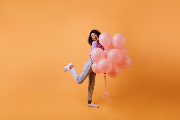 Zmysłowa afrykańska dziewczyna pozuje z różowymi balonami z helem Kryty strzał wspaniałej brunetki tańczącej na imprezie