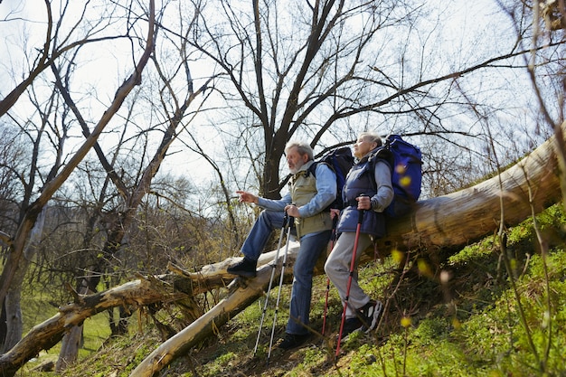 Znajdź najlepszy sposób na życie. Starsza rodzina para mężczyzna i kobieta w strój turystyczny spaceru na zielonym trawniku w pobliżu drzew w słoneczny dzień