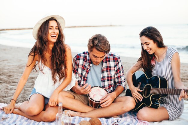 Znajomi na plaży z gitarą i bębnem