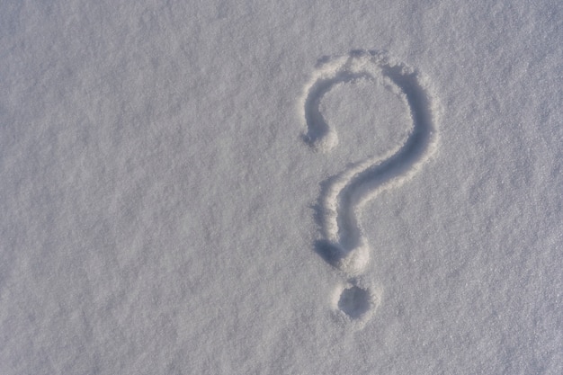 Znak zapytania na białym świeżym śniegu w zimie. znak zapytania na naturalnej powierzchni śniegu, kopia tło miejsca
