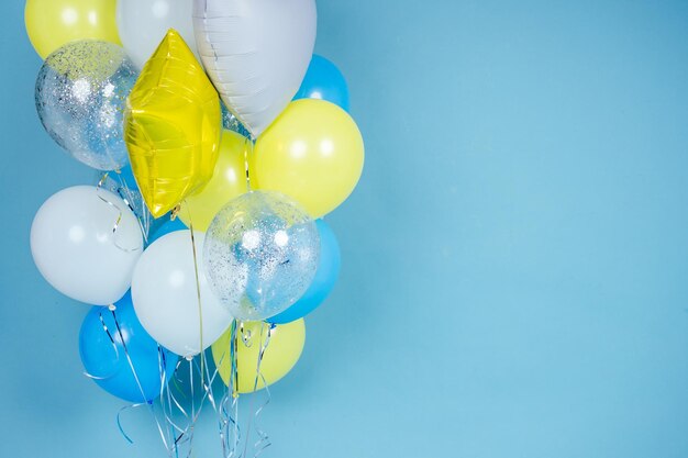 Żółte, niebieskie i białe balony na niebieskim tle ściany kopii przestrzeni. kolorowy balon w pokoju przygotowanym na przyjęcie urodzinowe. balony z helem copyspace