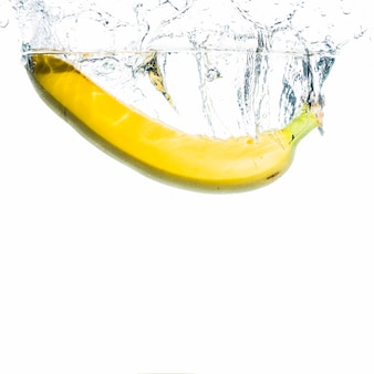 Żółty bananowy chełbotanie w wodę przeciw białemu tłu