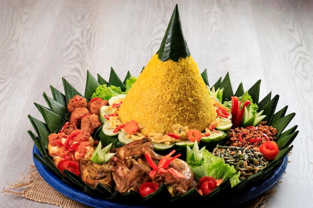 Żółty ryż w kształcie stożka. w indonezji nazywana „nasi tumpeng” świąteczna indonezyjska potrawa z ryżu z dodatkami