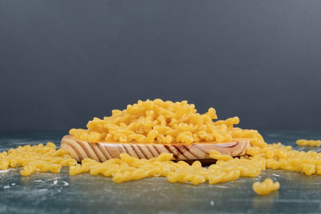 Żółty surowy makaron fusilli na drewnianym talerzu. Wysokiej jakości zdjęcie