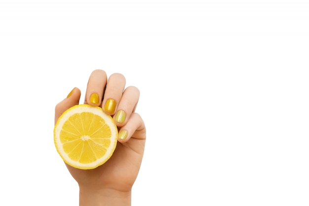 Żółty wzór paznokci. Ręka z brokatem manicure trzyma cytrynę