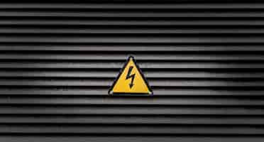 Bezpłatne zdjęcie Żółty znak niebezpieczeństwa na czarnej ścianie w paski