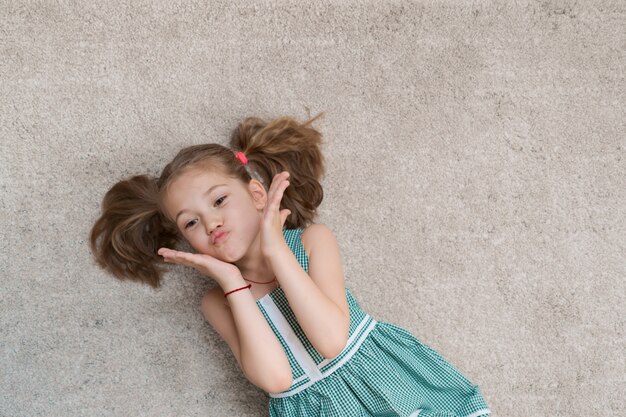 Zrelaksowana mała dziewczynka leży na podłodze w pomieszczeniu i uśmiecha się