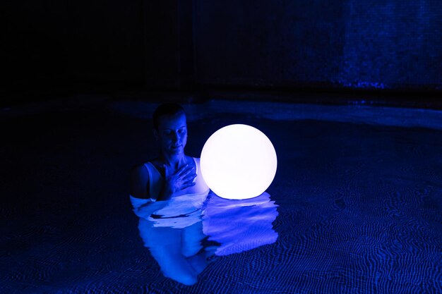 Zrelaksowana młoda kobieta w basenie z neonowym światłem