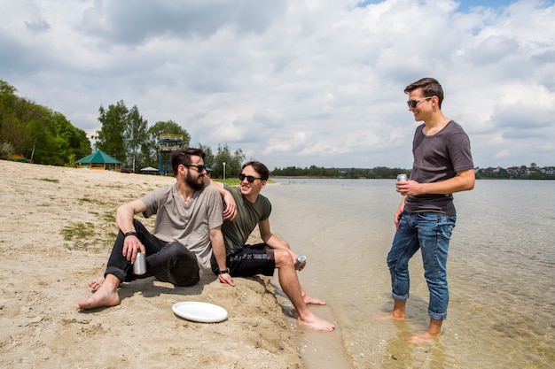 Bezpłatne zdjęcie zrelaksowani przyjaciele z napojami na plaży