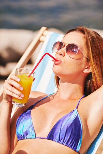 Zrelaksowany kobieta pije sok na plaży