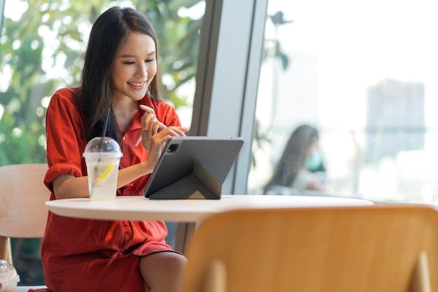 Zrelaksuj się, atrakcyjna, inteligentna azjatycka kobieta-przedsiębiorca niezależny uśmiech i ciesz się pracą ze smartfonem i laptopem w kawiarni z koncepcją rozmycia miasta biznes cyfrowy nomad dorywczo pomysły