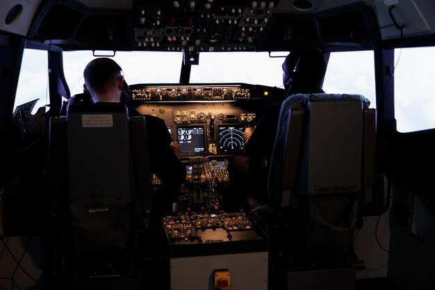 Zróżnicowany zespół członków załogi, używający poleceń sterujących, aby latać samolotem w kokpicie samolotu, naciskając przyciski zasilania na desce rozdzielczej. Kapitan i pilot robi pracy zespołowej latający samolot z dźwignią silnika.