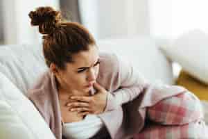Bezpłatne zdjęcie zrozpaczona kobieta z bólem w klatce piersiowej, leżąc na kanapie w salonie