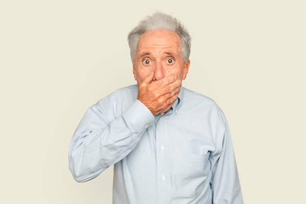 Zszokowany starszy mężczyzna z ręką zakrywającą usta