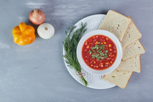 Zupa fasolowa w sosie pomidorowym z kromkami chleba i ziołami.
