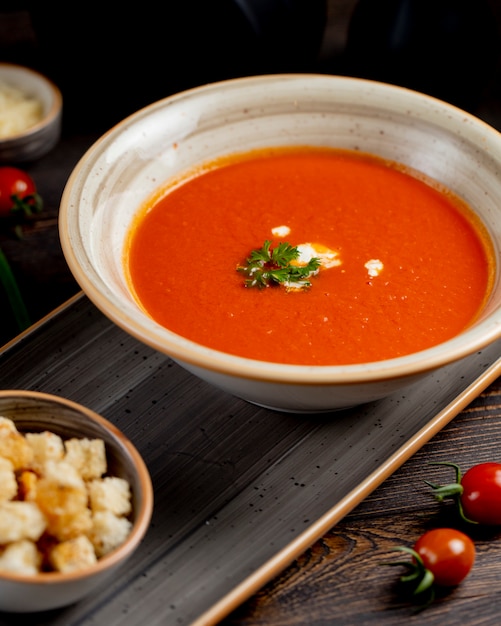 Zupa pomidorowa podawana z zieleniną i krakersami