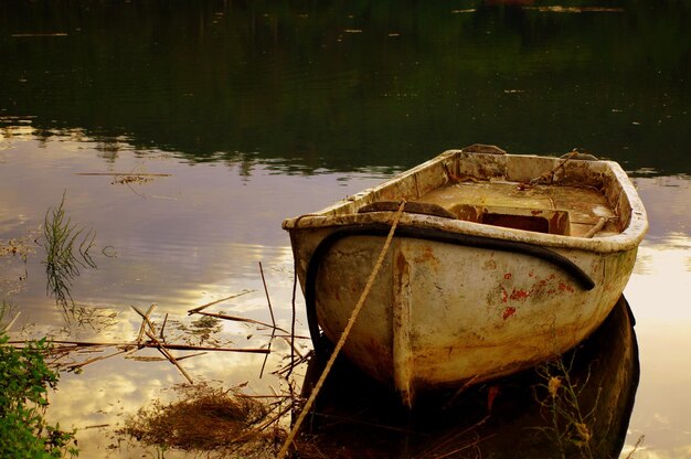 Bezpłatne zdjęcie zwietrzała zardzewiała i stara opuszczona łódź na jeziorze w parku
