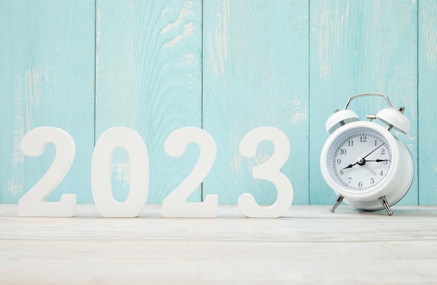 '2023' hecho con números de plástico y un reloj despertador en una madera azul