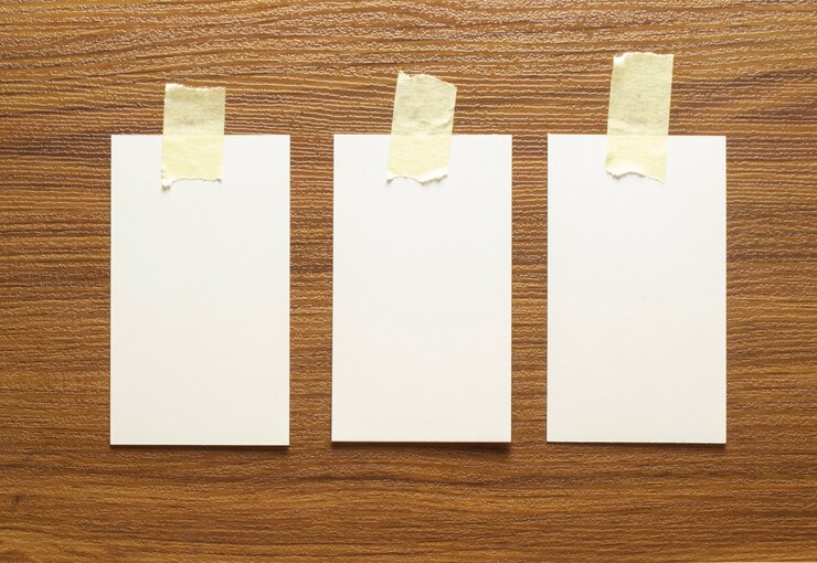 Foto gratuito 3 tarjetas de visita en blanco pegadas con cinta amarilla sobre una superficie de madera, tamaño de 3,5 x 2 pulgadas