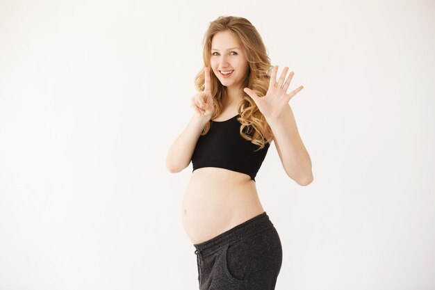 6 meses de embarazo. Retrato de feliz joven madre embarazada guapa con cabello largo rubio en ropa acogedora