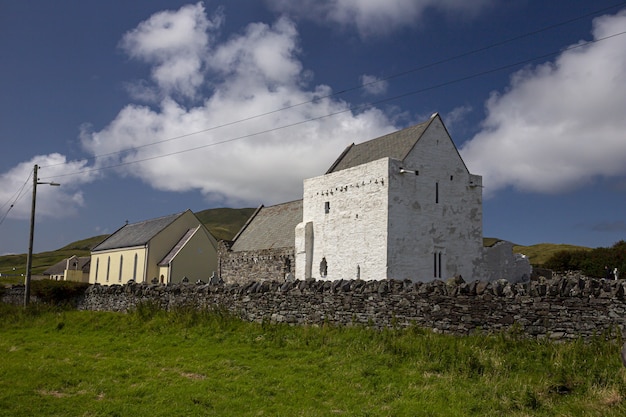 La abadía de Clare Island rodeada de vegetación bajo un cielo azul y la luz del sol en Irlanda