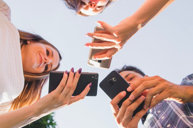 Desde abajo vista de los adolescentes con teléfonos inteligentes