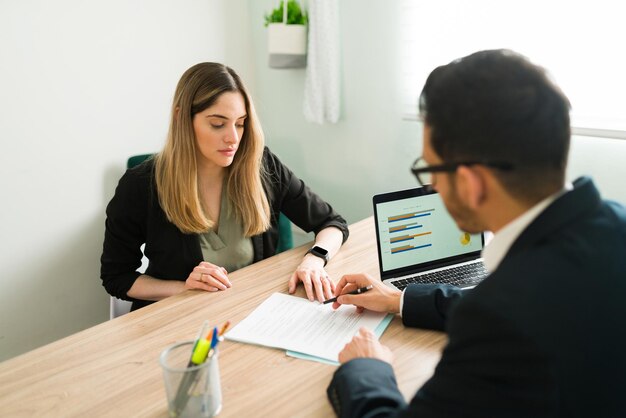 Abogada profesional explicando y revisando un contrato comercial con una clienta en la oficina. Mujer caucásica escuchando a su jefe masculino hablar sobre un informe de trabajo