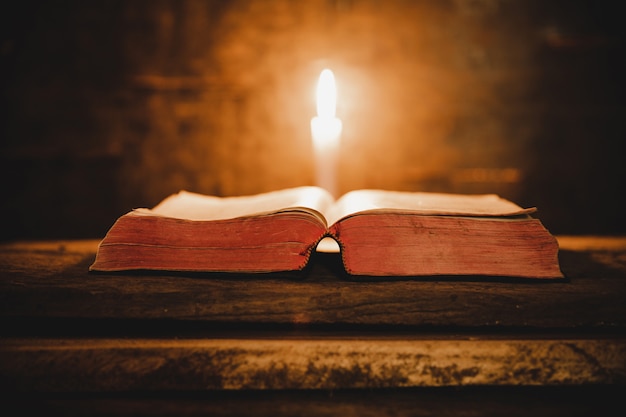 Abra la biblia santa y la vela en una tabla de madera del roble viejo.