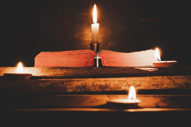 Foto gratuita abra la biblia santa y la vela en una tabla de madera del roble viejo.