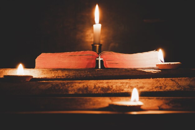 Abra la biblia santa y la vela en una tabla de madera del roble viejo.