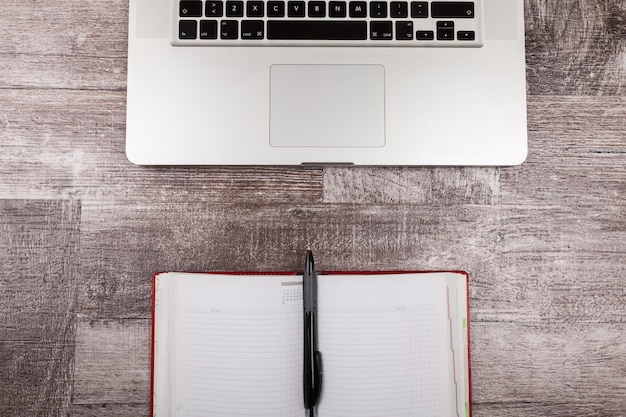 Abra el cuaderno de escritura junto a una computadora portátil desde arriba sobre un fondo de madera