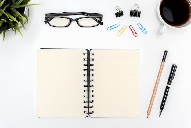 Abra el cuaderno espiral en blanco sobre mesa de escritorio blanco