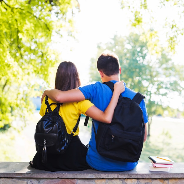 Abrazando a adolescentes sentados en la cerca