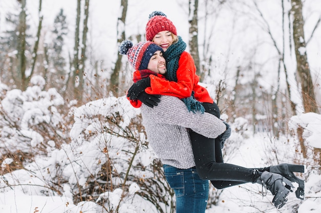 Abrazando a feliz pareja en el bosque de invierno