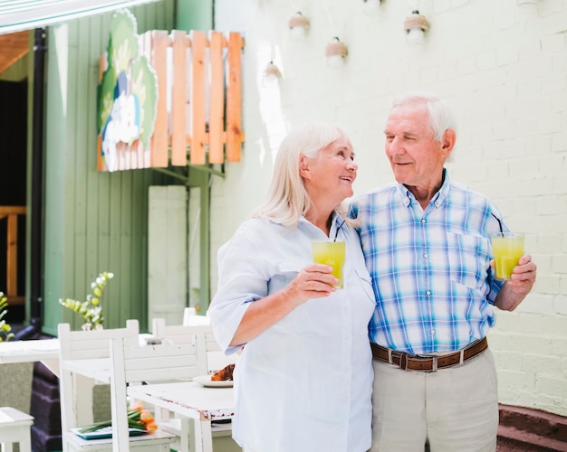 Foto gratuita abrazando pareja de ancianos bebiendo jugo en la cafetería