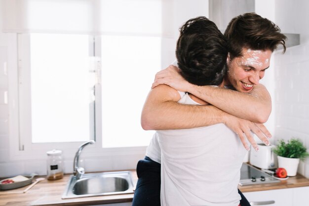 Abrazando a una pareja gay en la cocina
