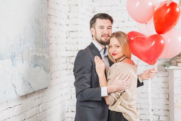 Abrazando pareja con manojo de globos
