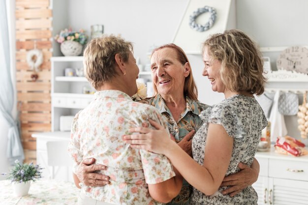 Abrazando sonrientes mujeres multigeneración en casa