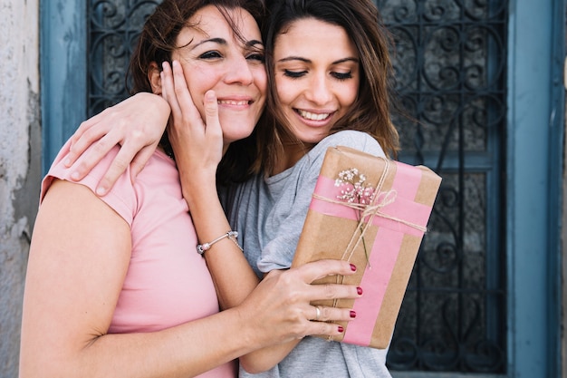 Abrazar a las mujeres con un regalo cerca de la puerta