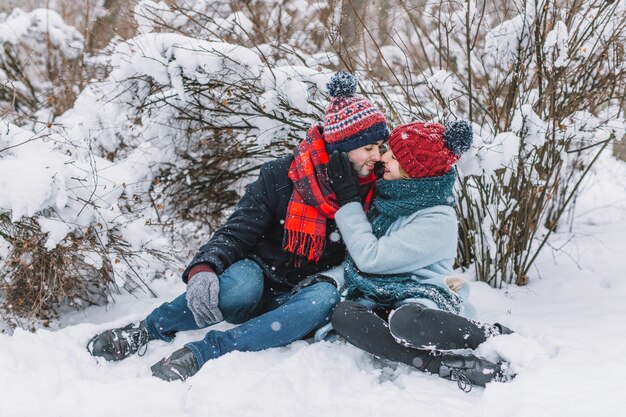 Abrazar pareja amorosa sentada en la nieve