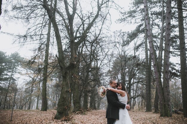 Abrazar recién casados ​​en un bosque sin hojas