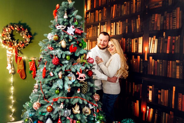 Abrazo de pareja se encuentra delante de un árbol de Navidad