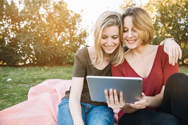 Foto gratuita abrazo de tableta de exploración de mujeres en el parque