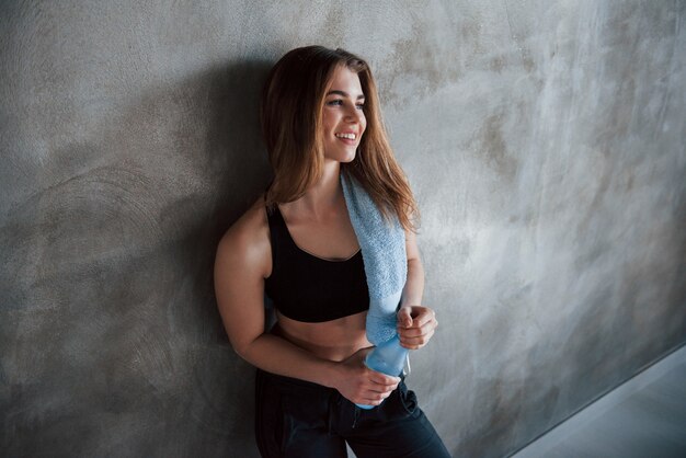 Abriendo la botella con agua. Foto de hermosa mujer rubia en el gimnasio en su fin de semana