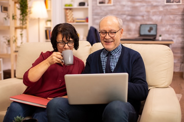 Abuela y abuelo usando una computadora portátil para charlar con sus nietos. Personas mayores que utilizan tecnología moderna.