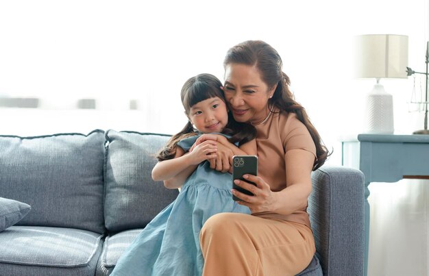 Abuela asiática feliz usando un teléfono inteligente tomando una foto selfie nieta juntos