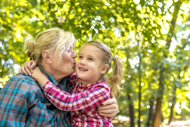 Abuela besando a su linda nieta en un parque en un día soleado